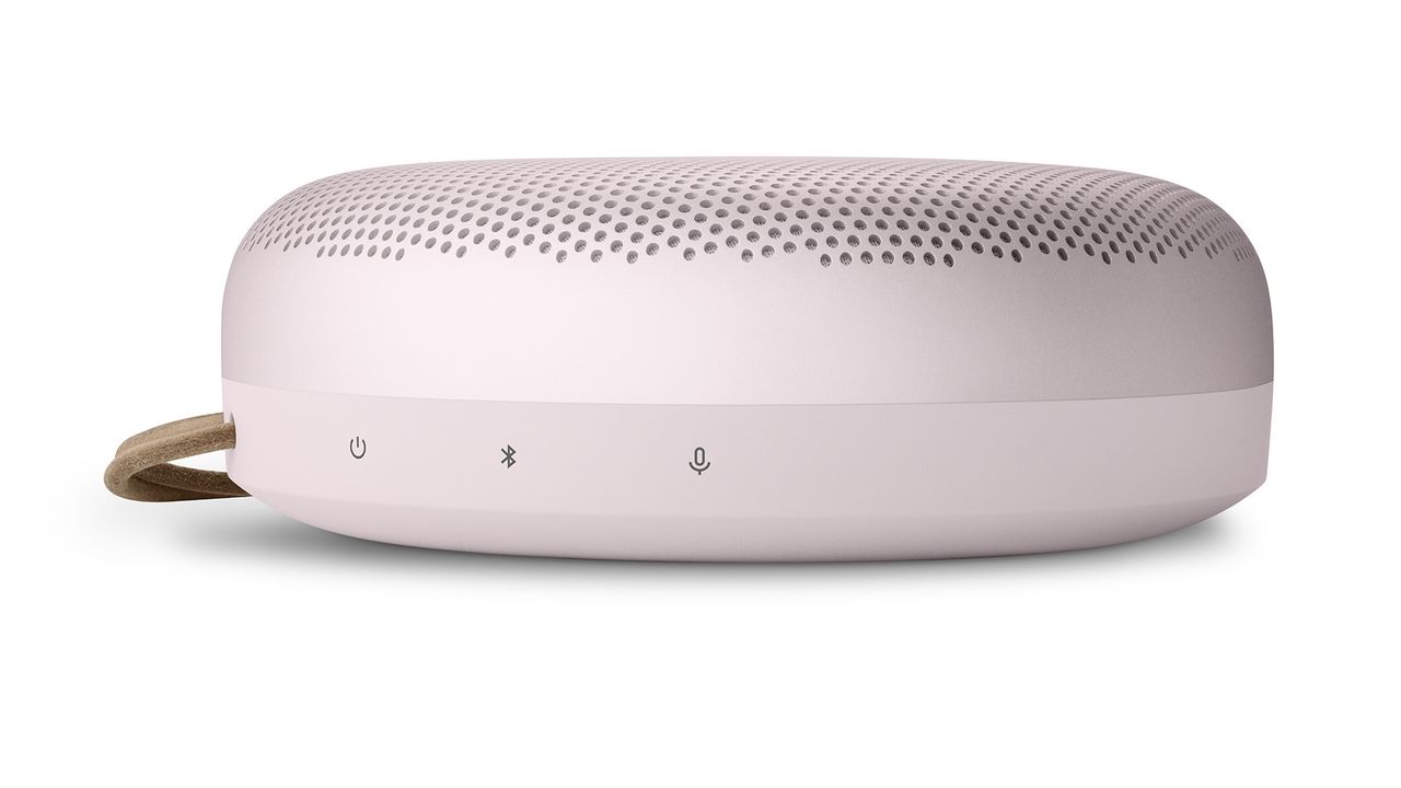 The side of a pink Bang &amp; Olufsen Beosound A1 (2nd Gen) showing some of the controls. The strap is just visible on the left side. The background is white.