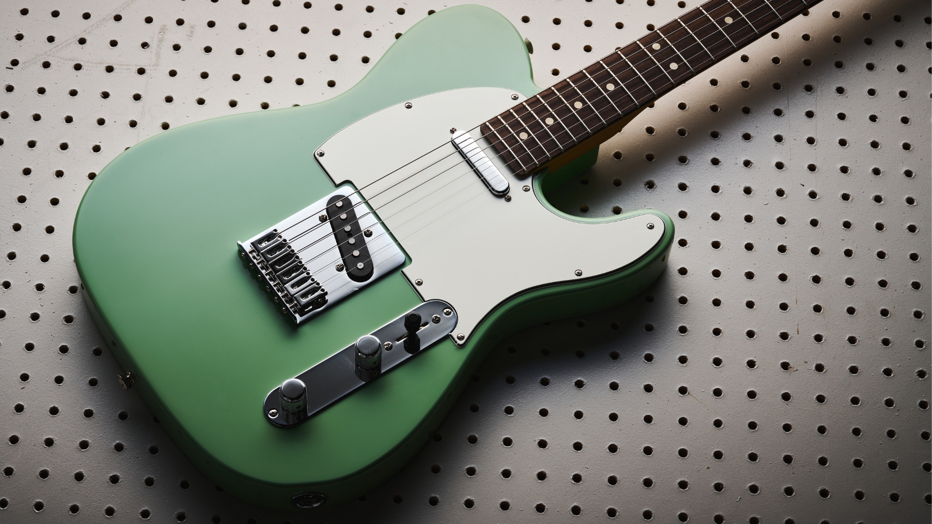 A Fender Player II Telecaster electric guitar lying on a white pegboard