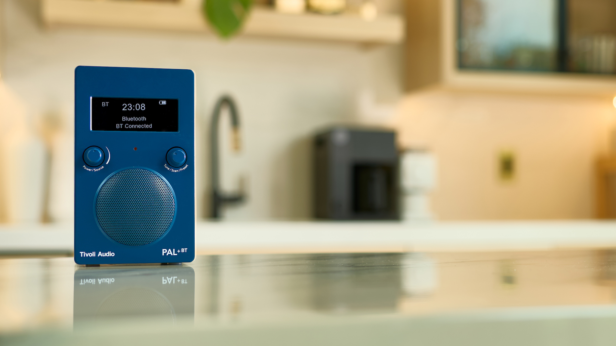 Lifestyle image of the Tivoli Audio PAL+BT in blue on a kitchen island with the background slightly out of focus