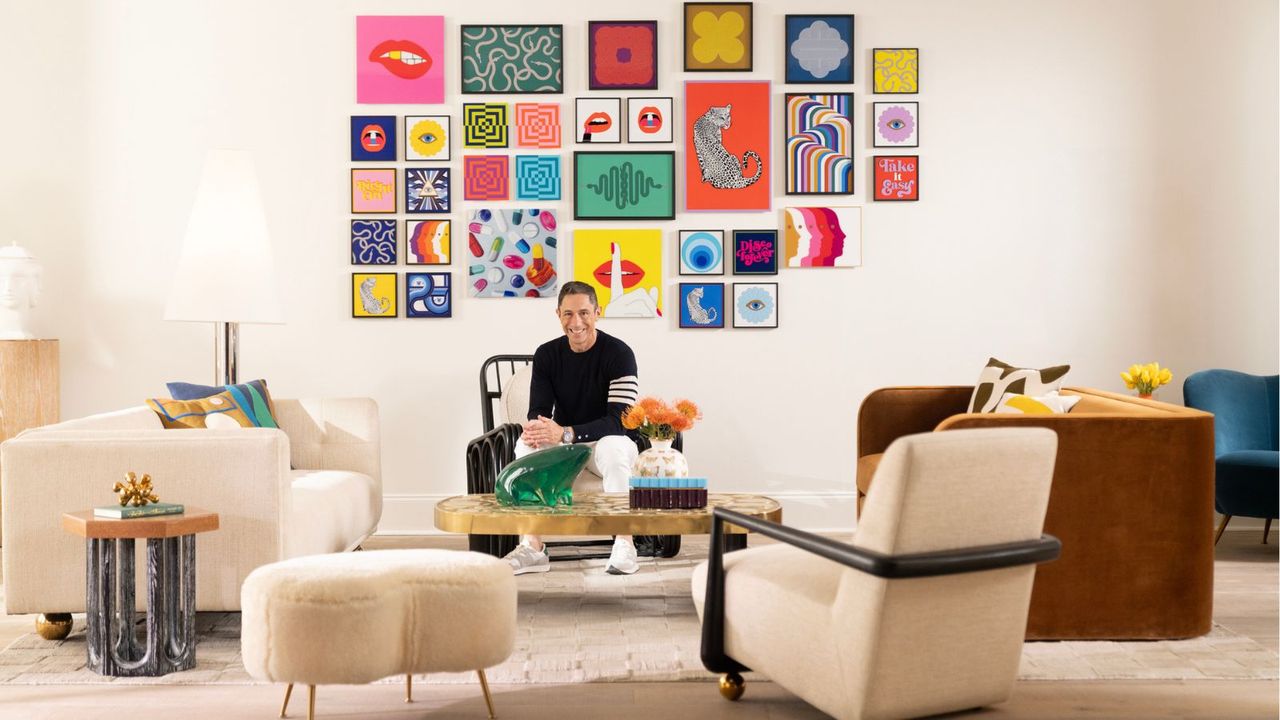 Designer Jonathan Adler sitting in a living room in front of a bright, colorful gallery wall