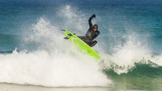 Surfers riding waves wearing wetsuits
