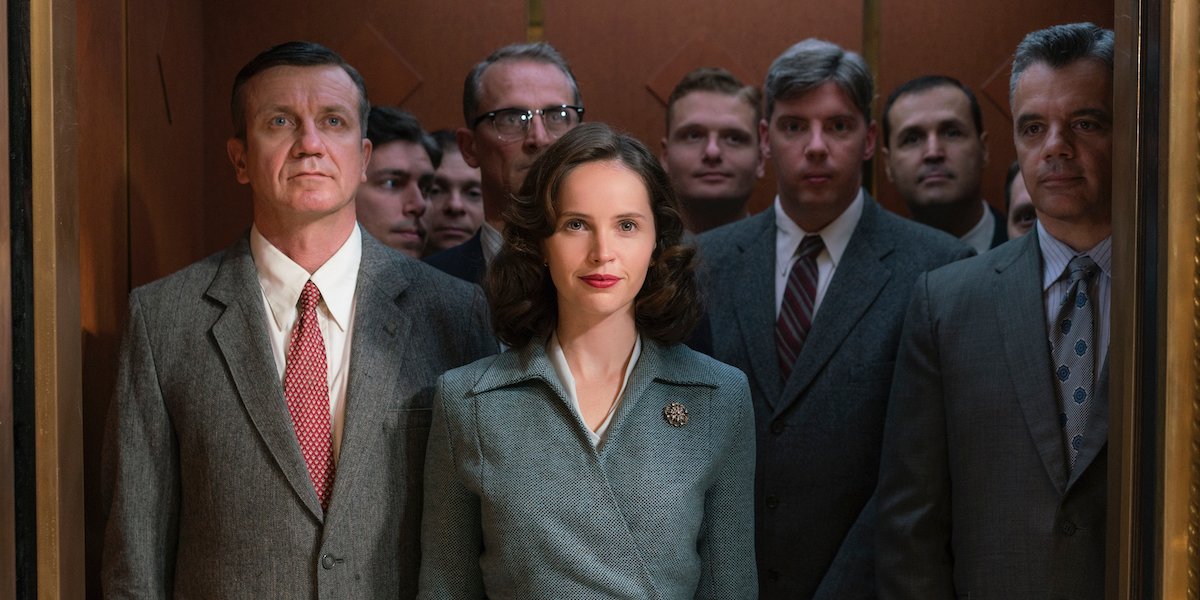 Ruth Bader Ginsburg (Felicity Jones) smiles while standing in an elevator full of men in &#039;On The Basis of Sex&#039;