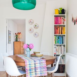 white dining area with table, chairs and vertical bookcase
