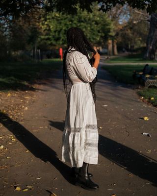 Influencer styles a white maxi dress with black knee boots