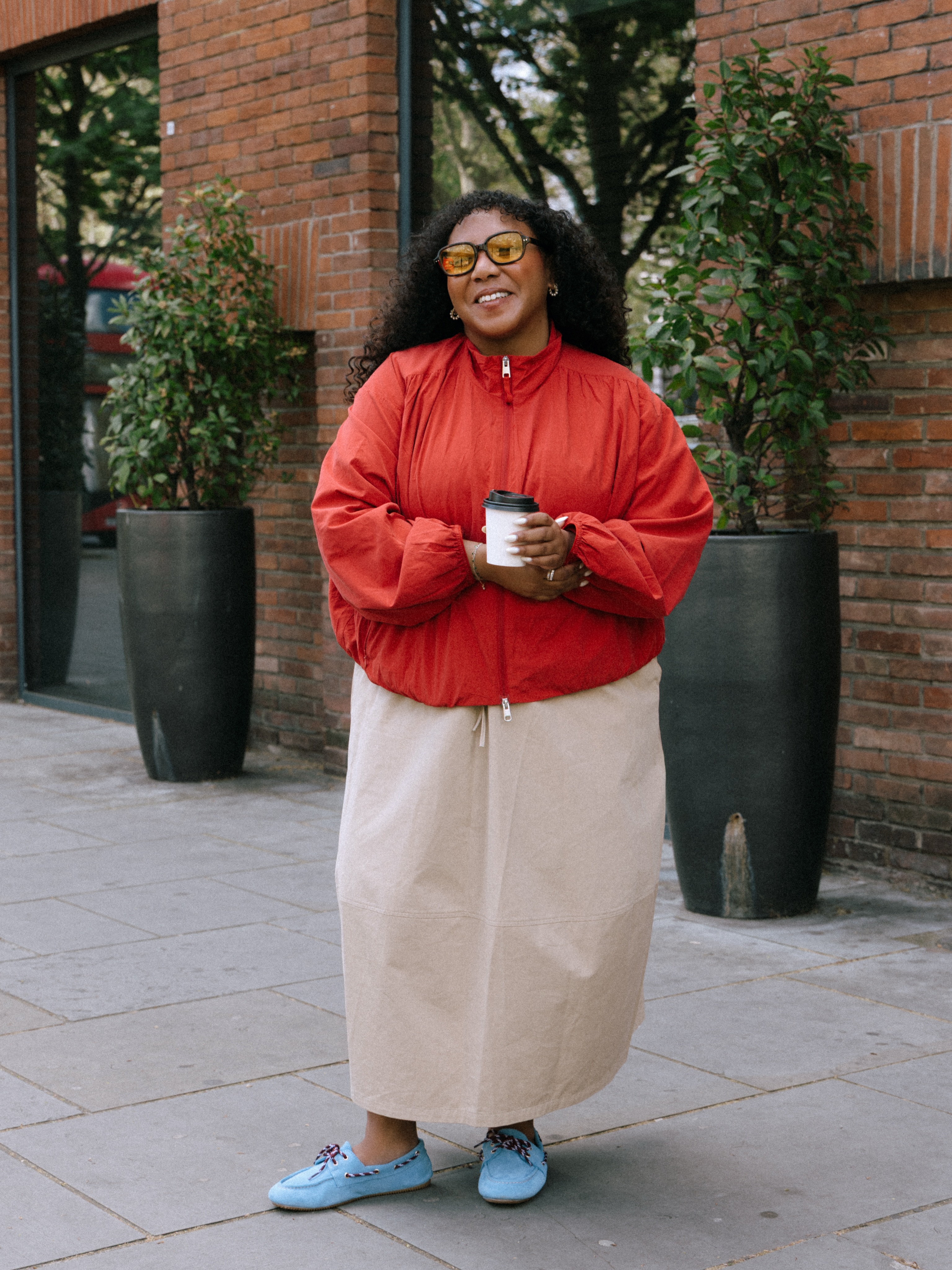 nicoleocran wears a red jacket, beige maxi skirt and blue boat shoes
