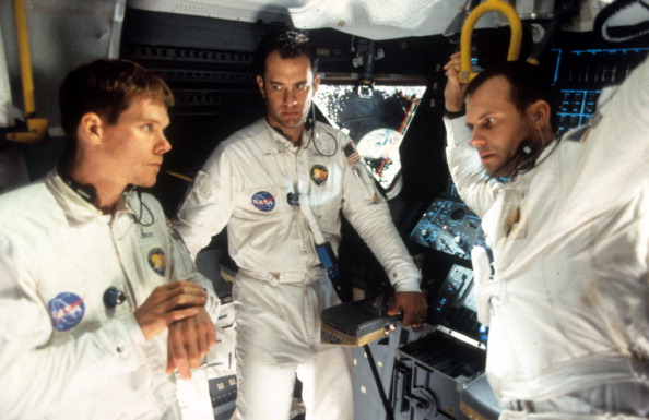 three astronauts in a spacecraft with the earth visible in the window. they look tensely at each other