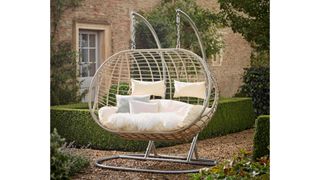 Cox & Cox Indoor Outdoor Double Hanging Chair in a stylish manicured garden with a house in the background