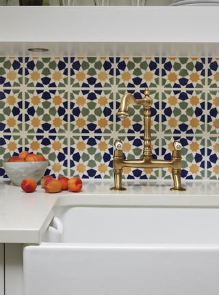 Patterned tile backsplash behind sink and faucet in kitchen