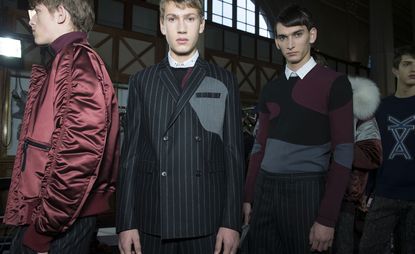 男模们身着Kris Van Assche 2015秋冬系列的红色夹克、黑色条纹西装和几何图案套头衫