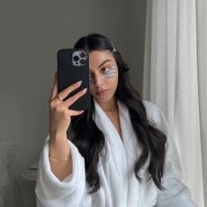 Woman wearing Dior eye patches while taking a mirror selfie