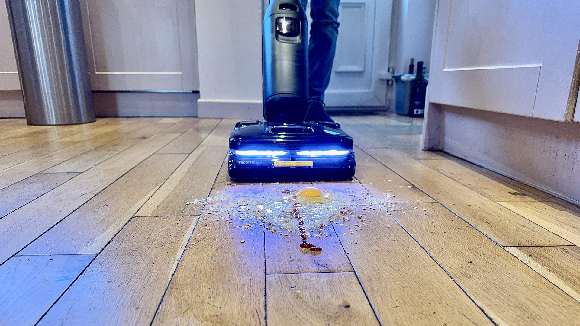 Roborock F25 Ultra clearing a mess of egg, oats, ketchup and more from an engineered wooden floor
