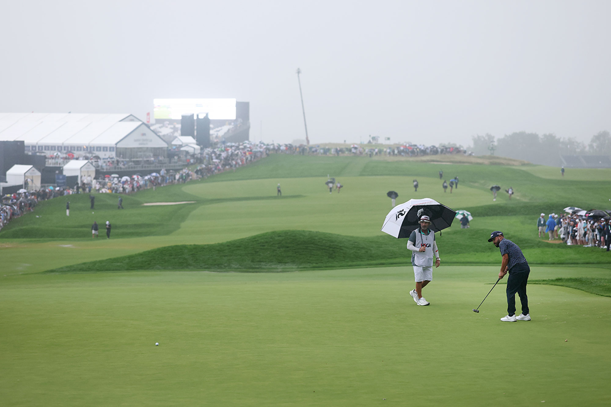 JJ Spaun watching his long putt that would eventually lead to birdie and a US Open win at Oakmont Country Club, with rain pouring down and the course very wet