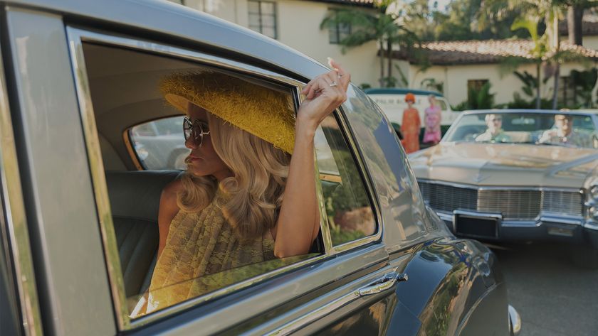 Kristen Wig wears a yellow hat while sitting in the back of a Rolls Royce in Palm Royale season 2