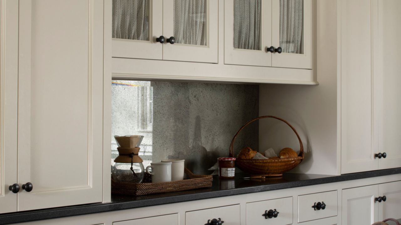 Close-up image of white kitchen cabinetry with black countertops. There are a couple of woven baskets on the counter with ceramic jars and produce in them