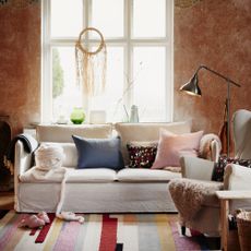 folklore fusion image of a living room, with a beige/grey sofa, brown walls, a large window, and a colourful geometric rug