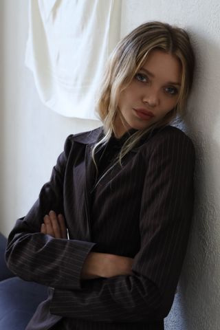 actress and fashion entrepreneur jessie andrews leans against a wall and wears a black blazer