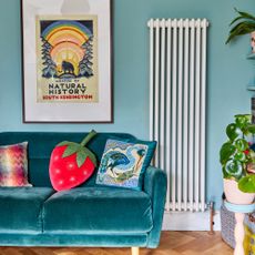 A living room with a velvet sofa, graphic cushions, a wall print and a large radiator