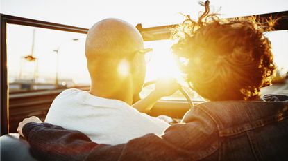 A semi-retired couple drives into the sunset in a convertible.