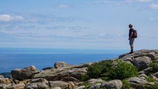 A hiker looking at the ocean from the summit of Cadillac Mountain