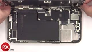 A screenshot from a PBKreviews video showing the iPhone 14 Pro Max's display being lifted up, revealing the components inside the phone