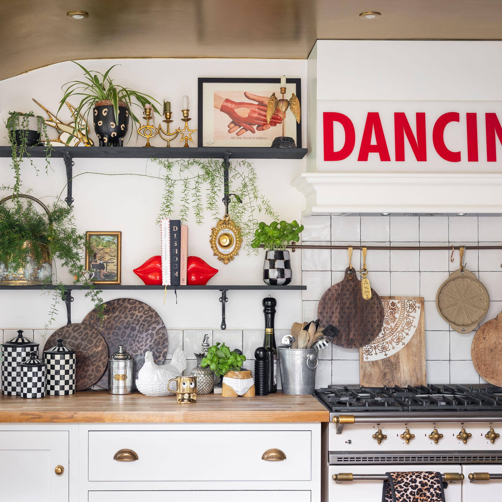 White kitchen with gold ceiling, black shelves and playful accessories