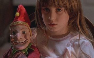 A little girl holds a jester doll in 'Dolls'