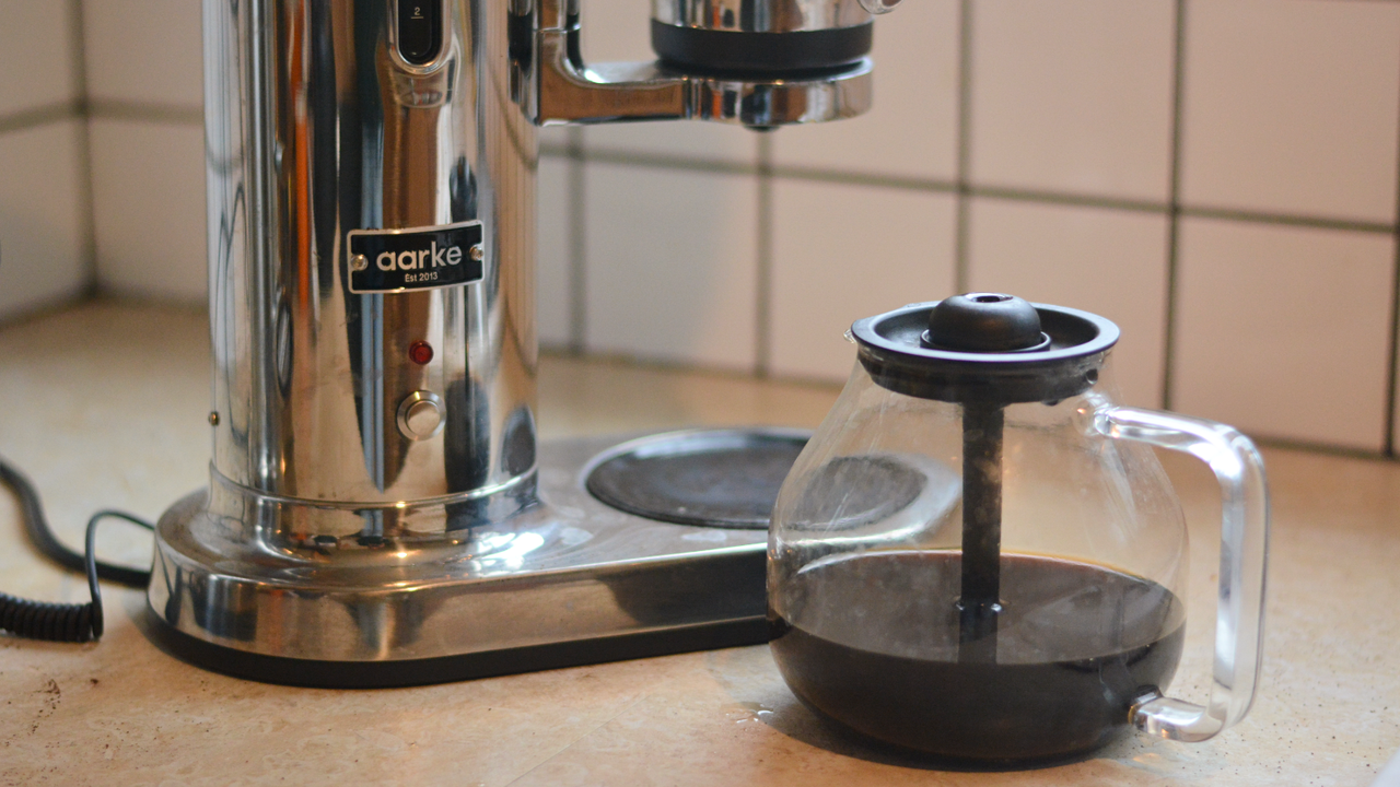 Image of the Aarke Coffee System &ndash; a stainless steel coffee bean grinder and drip coffee maker &ndash; positioned on a kitchen counter