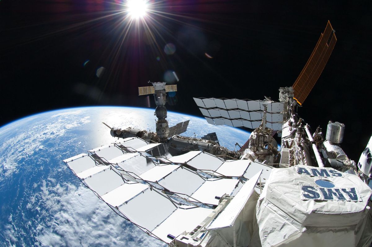 A photo of the Alpha Magnetic Spectrometer (AMS) experiment outside the International Space Station. NASA astronaut Ron Garan took this photo during a spacewalk on July 12, 2011. The space shuttle Atlantis is docked at the edge of the frame on the far right, and a Russian Soyuz spacecraft is docked to Pirs, below the sun.