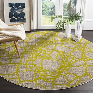 A gray and yellow round rug sits next to a white chair 