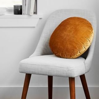 Fall throw pillow round velvet in golden colour on grey fabric chair 