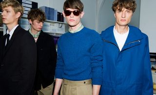 Male models wearing Margaret Howell S/S 2015 collection. The two models on the left are wearing black jackets and the guy next to them is wearing a blue jersey with sunglasses. Next to him the model is wearing a blue coat over a white t-shirt