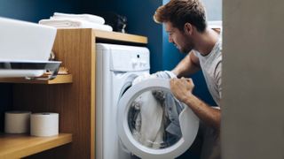 Man pulls laundry from a washer dryer