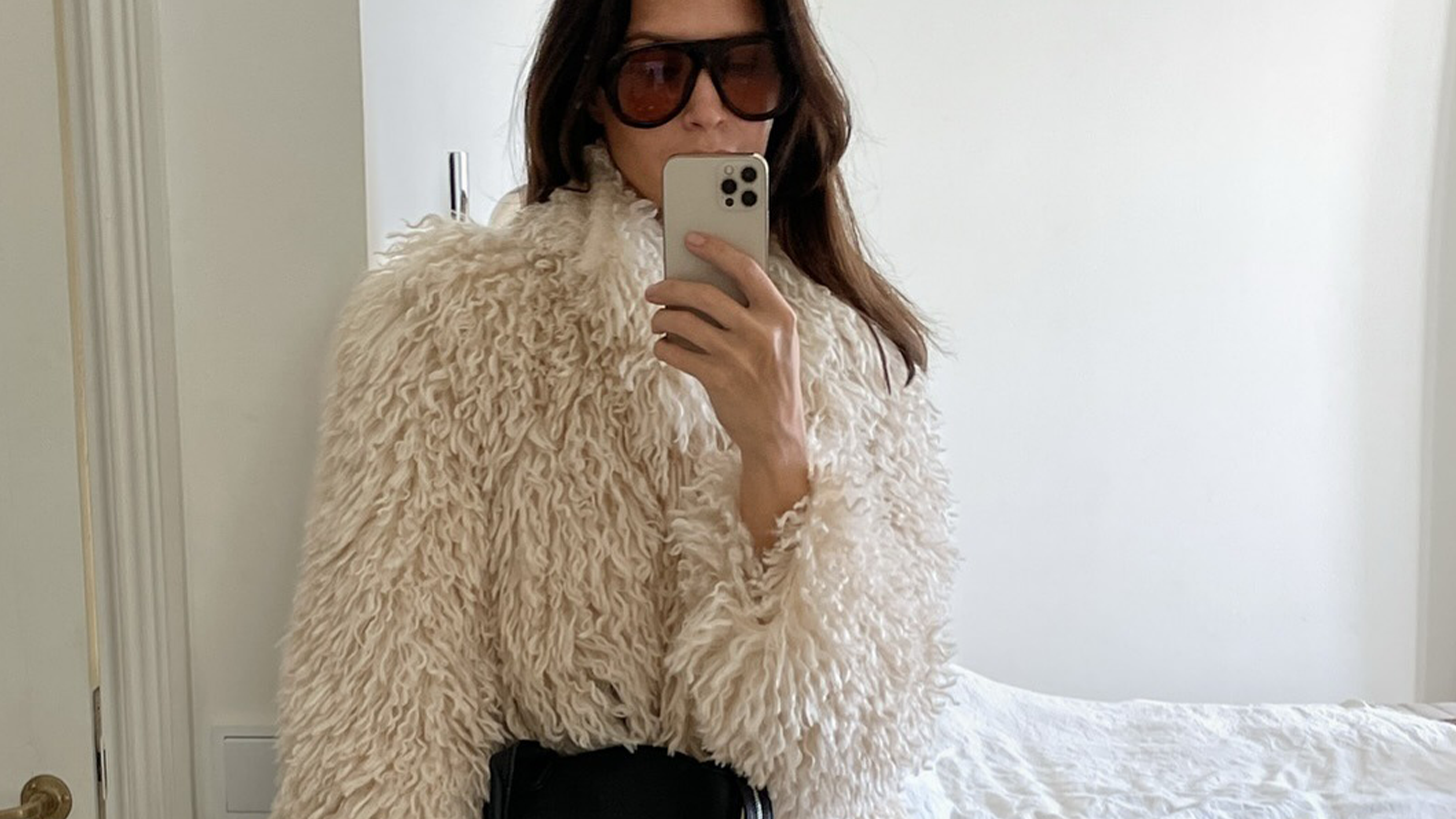 Woman wearing furry jacket and white denim jeans.