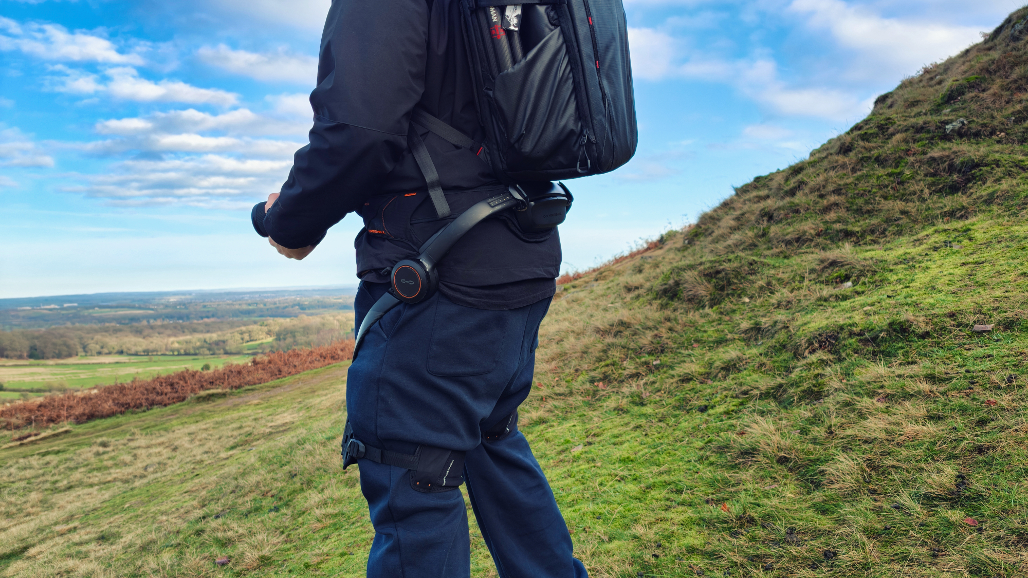 Person using a Hypershell X Ultra exoskeleton on a grassy hill