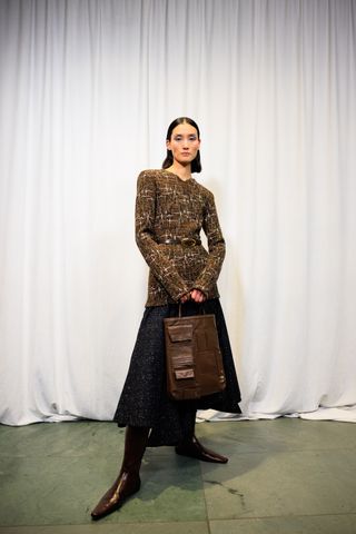 A photo of a model holding a brown leather Tory Burch cargo tote.