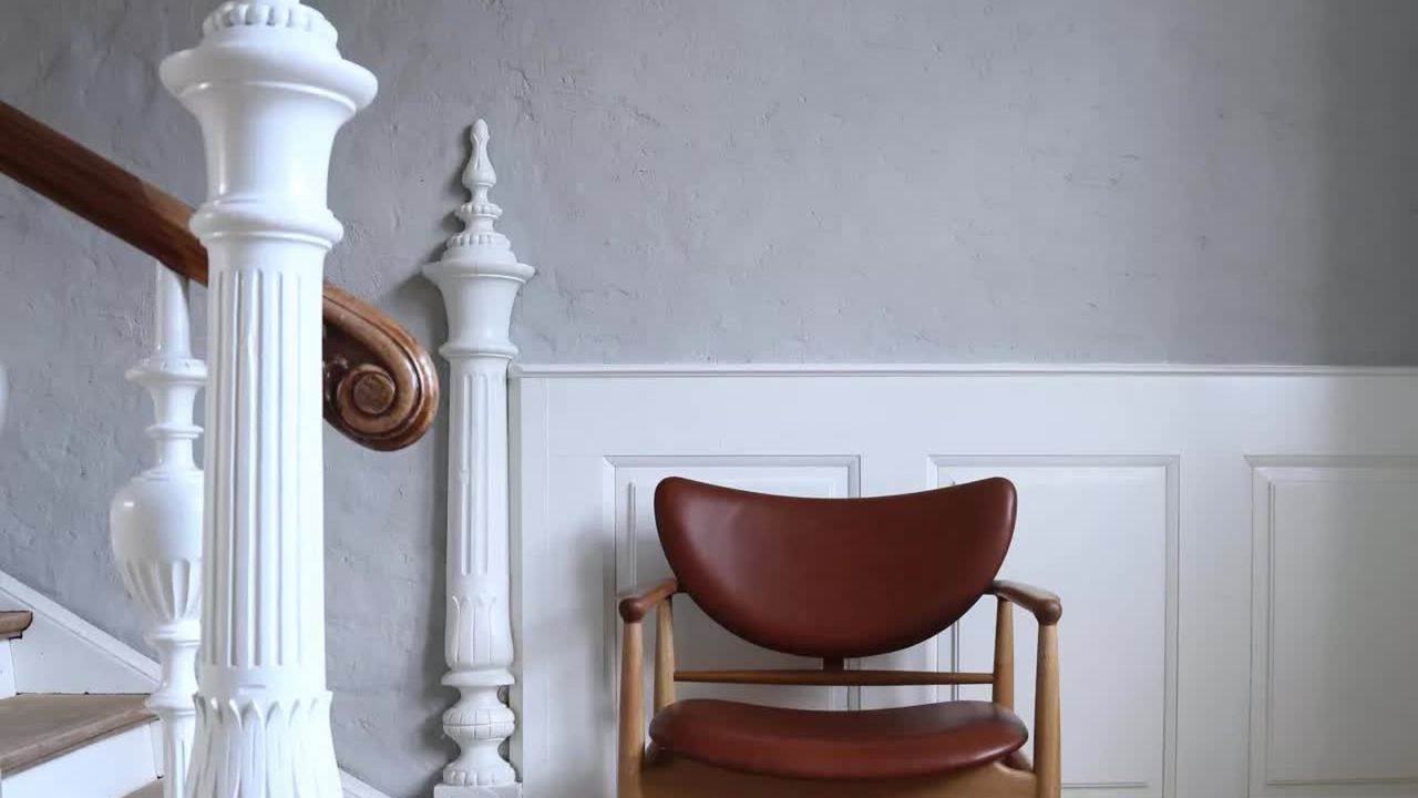 a grey hallway with a white bannister and leather chair, to illustrate the best washable paint options