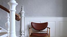 a grey hallway with a white bannister and leather chair, to illustrate the best washable paint options