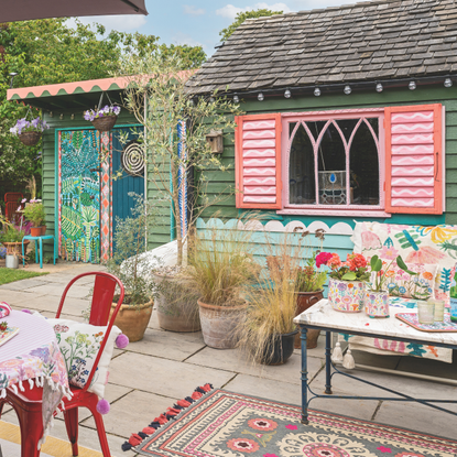 Blue and pink painted shed with potted plants