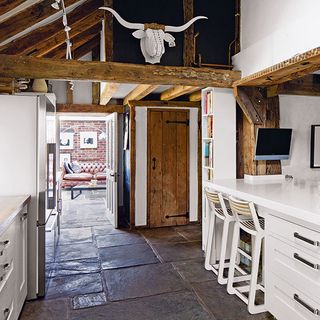 kitchen with oak beam interior white counter wooden door and stone floor