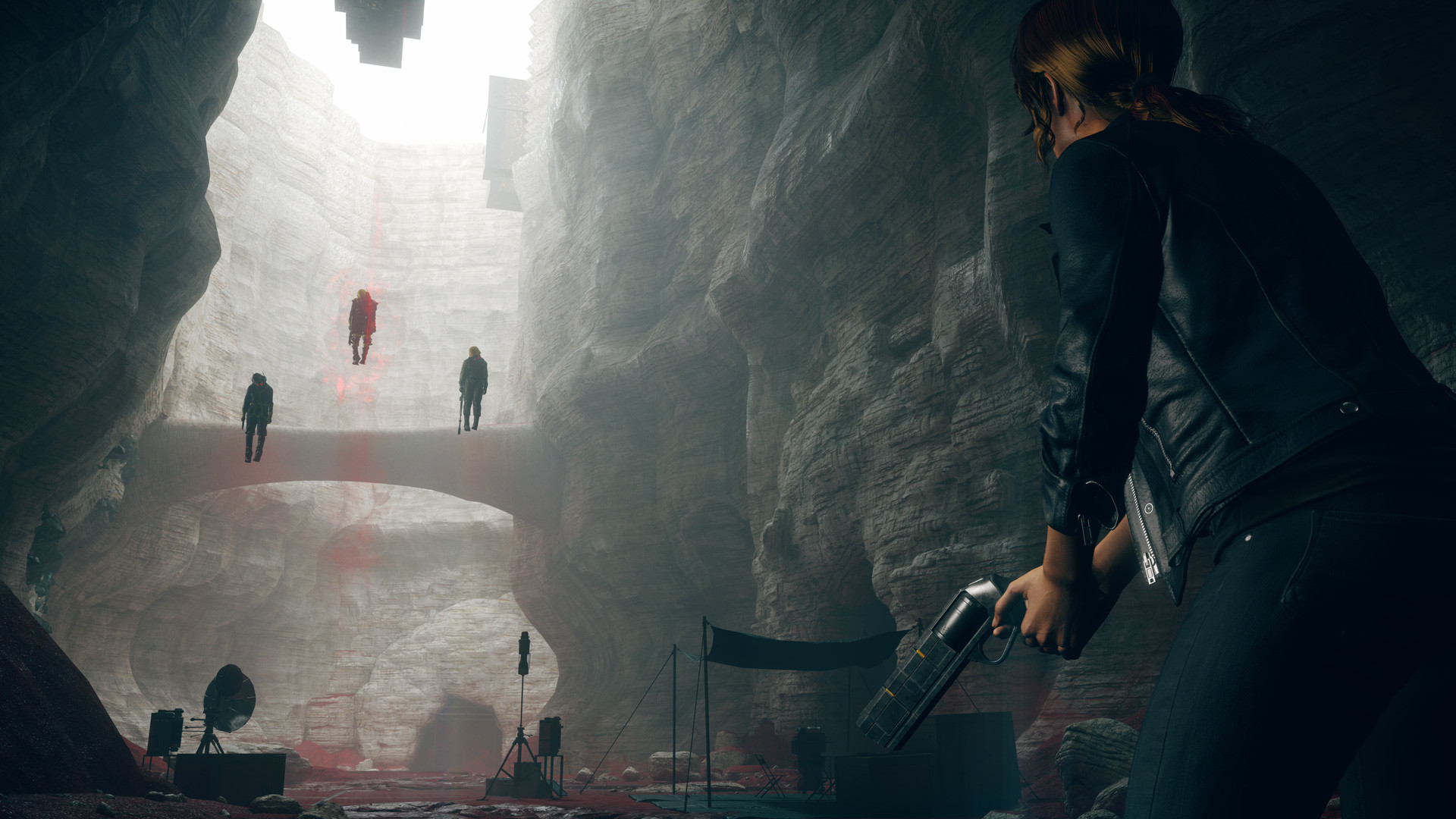 An agent holding a gun and looking at three floating bodies during a moment in the game, Control