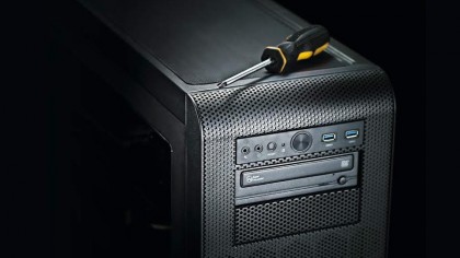 A tower PC against a black background with a screwdriver on top