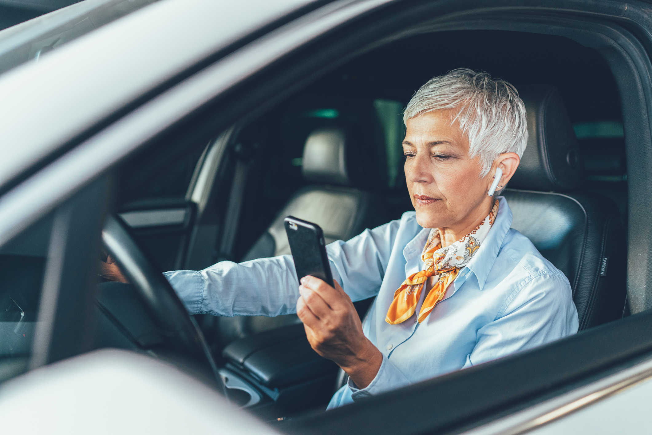 Woman looking at her phone while parked in a car. 
