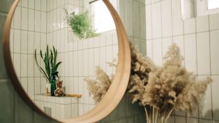 Green bathroom with a round mirror