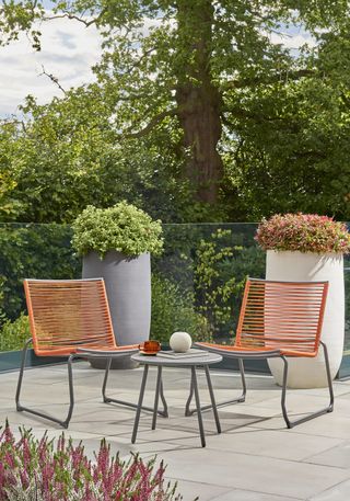 modern orange string bistro set on a modern patio with large planters