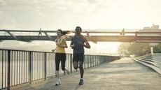 a man and woman run by the Thames River in London