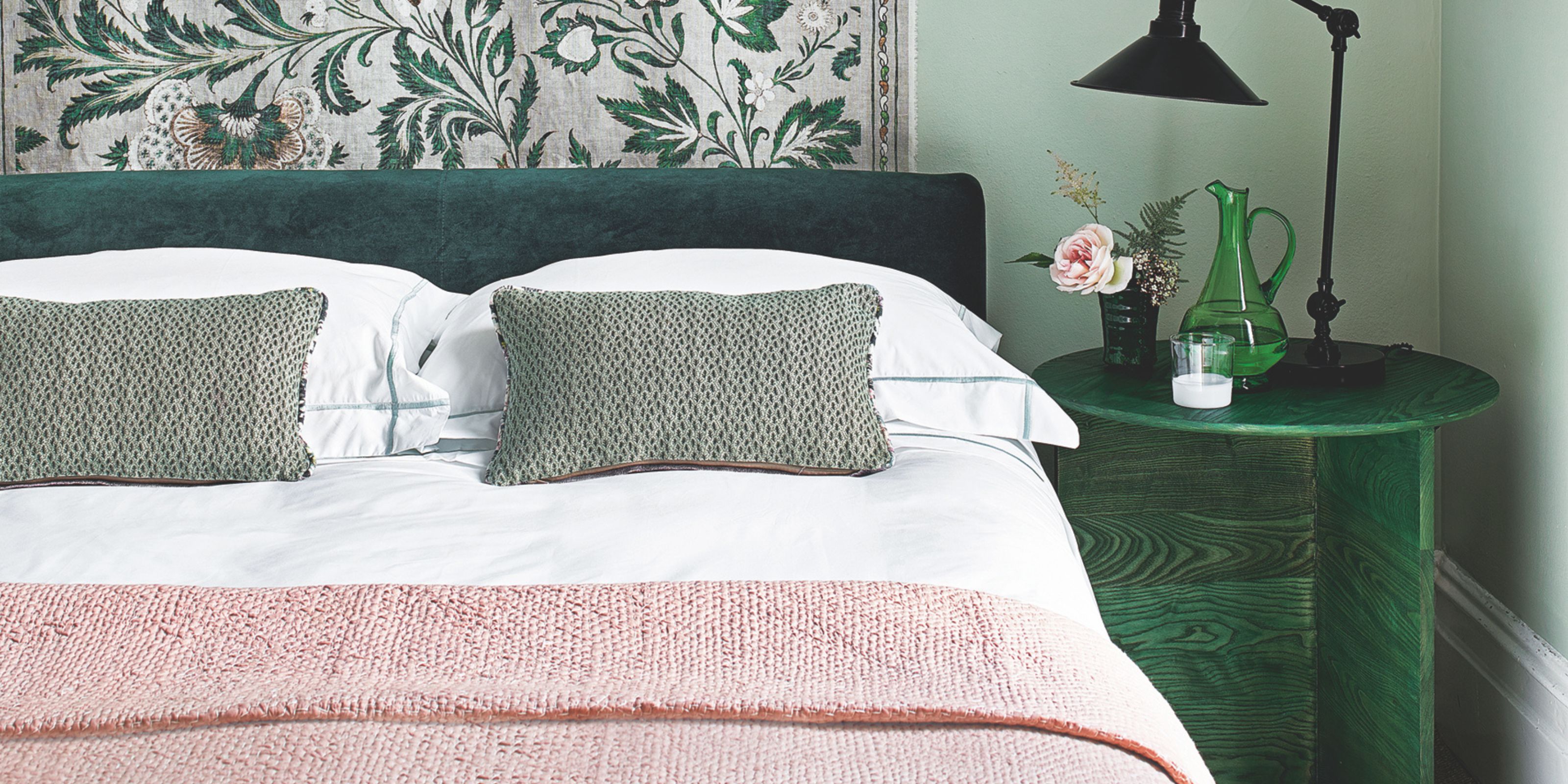 green bedroom with a made bed in the middle, with a white quilt and pink blanket