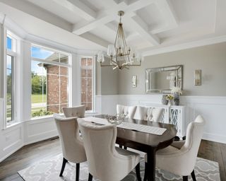 Clean dining room table with plush white chairs and a bay window