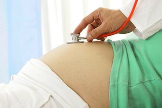 A stethoscope on a pregnant woman's belly