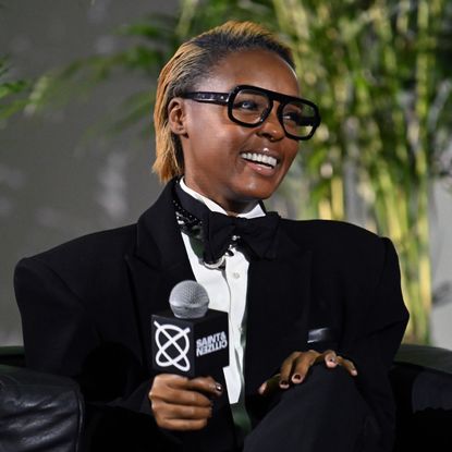 a black woman with short, honey blonde hair being interviewed on an event stage