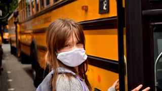 When do we go back to Back to school 2020 student with mask boarding a yellow bus